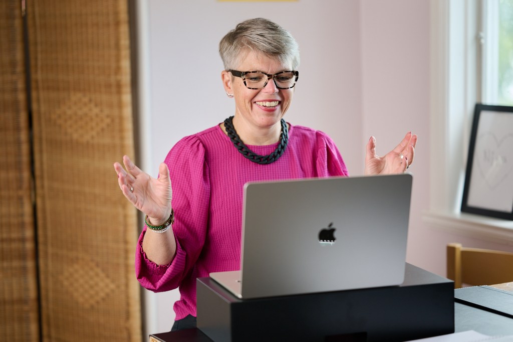 kvinna har teamsmöte vid datorn och gestekulerar stort.