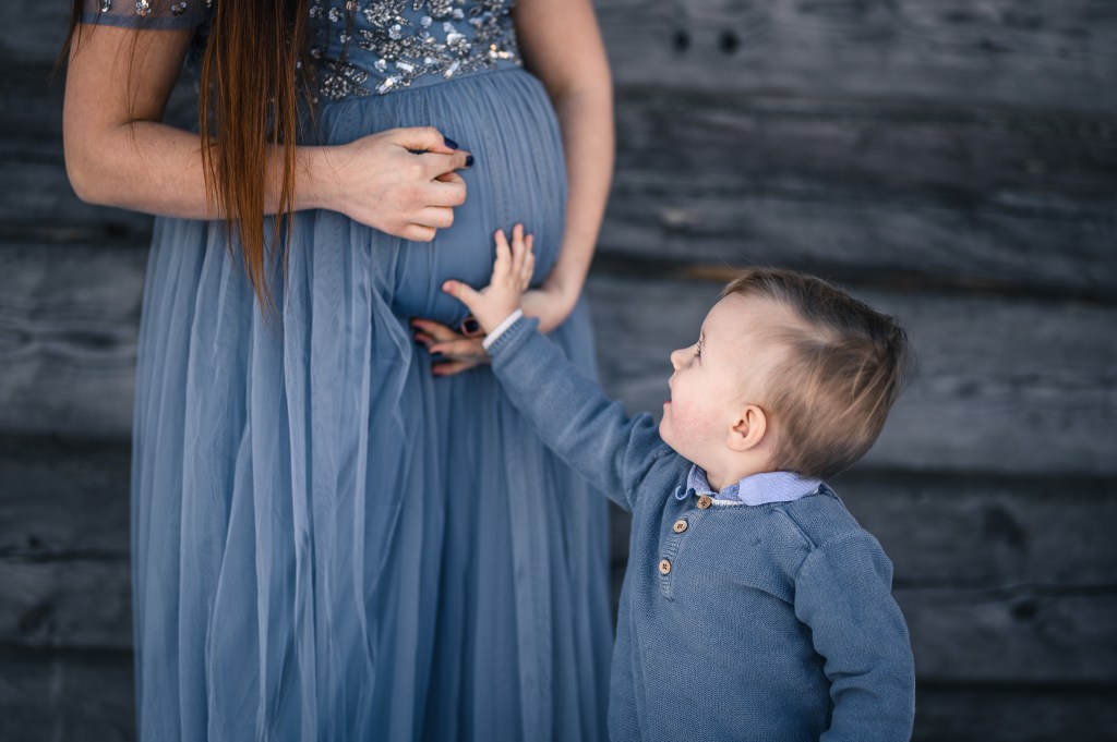 Barn håller handen på gravidmage.
