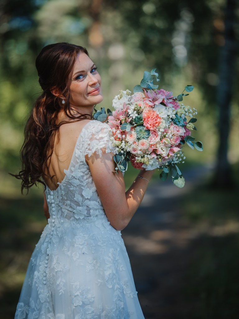 Brudporträtt i skogen på ett bröllop i dalarna, klänning, ansikte och blommor.