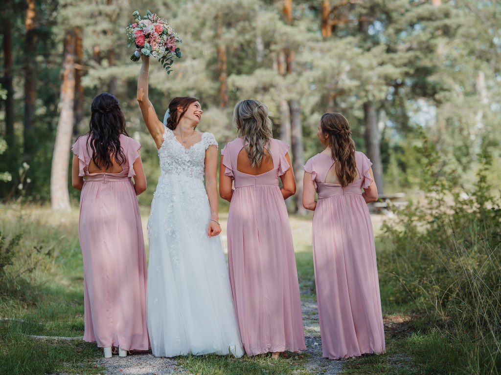 Bruden står vänd mot kameran och tärnorna tittar bortåt