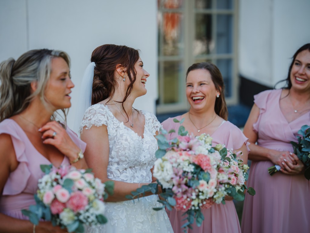 Bruden med sina tärnor står och skrattar utanför kyrkan