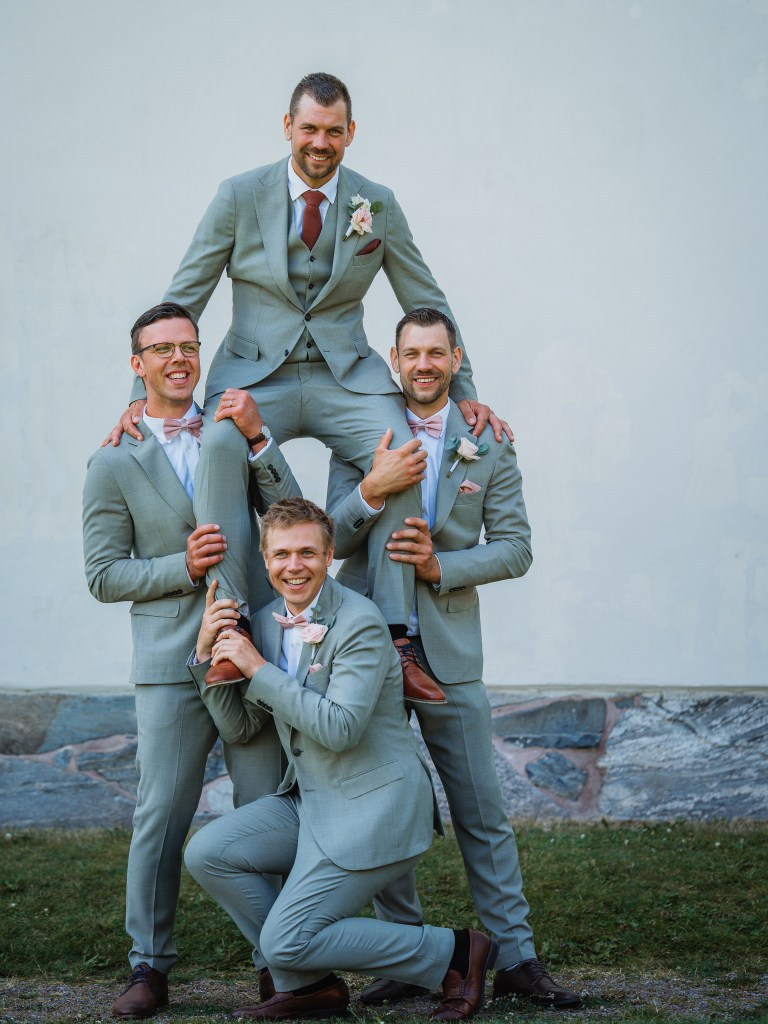Brudgummen med sina marskalker står i pryamidställning där dom lyfter upp brudgummen överst