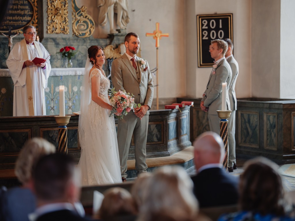 Brudparet står och ser ut på alla gäster i kyrkan