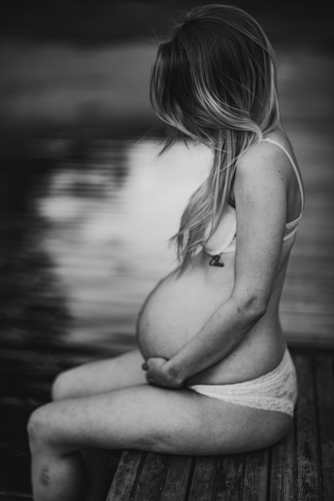 gravid kvinna på sitter på brygga. svartvitt fotografi.