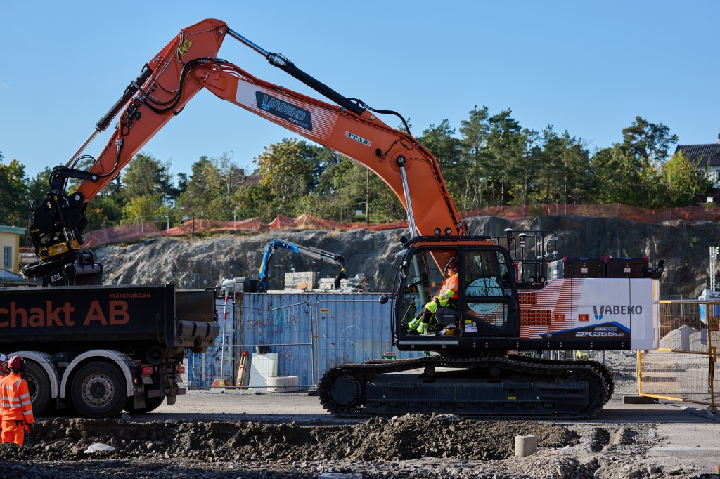 grävamaskin som lastar en lastbil på ett bygge i stockholm